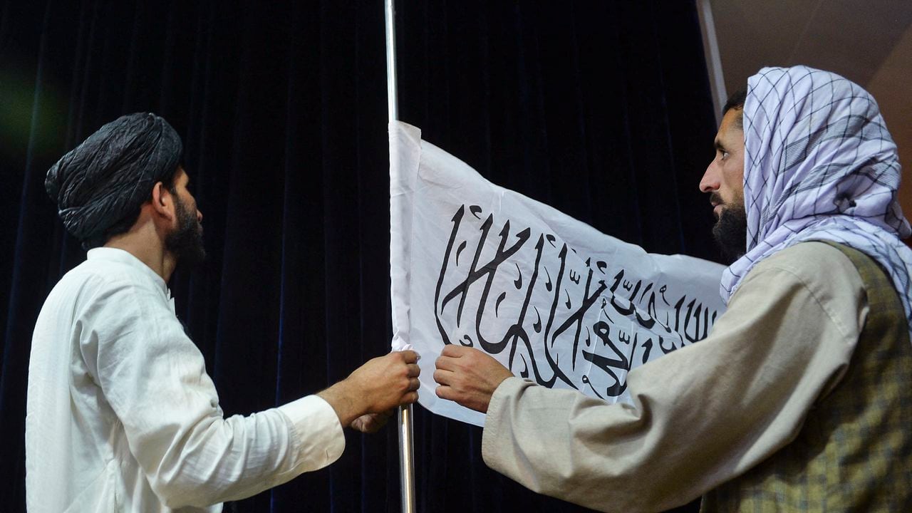 El portavoz talibán Zabihullah Mujahid poniendo una bandera del emirato talibán. (Photo by Hoshang Hashimi / AFP)