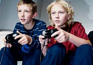 dos niños de 10 y 13 años jugando con videoconsolas.