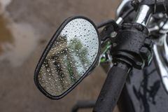 Reflection in the mirror. Raindrops on a motorcycle mirror. Traveling on two wheels. Motorcycle travel in any weather. Walk under the rain. Drops close up. The romance of biker life.