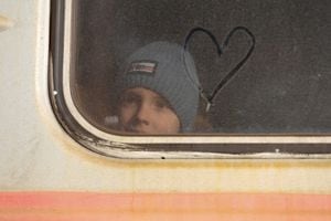 Un niño mira por la ventana cubierta de polvo de un tren junto al símbolo de un corazón representado en él, mientras los evacuados abordan un tren antes de salir de la ciudad de Donetsk, Ucrania, controlada por los rebeldes, el 20 de febrero de 2022. Foto REUTERS/Alexander Ermochenko

