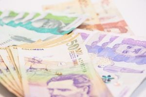 Billetes colombianos ordenados por valor en una mesa blanca
