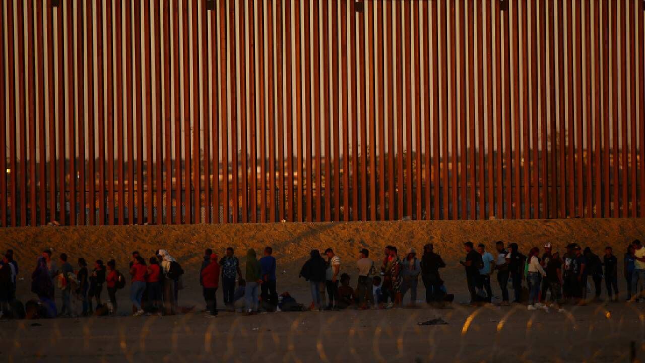 Migrantes que buscan asilo en Estados Unidos se reúnen cerca de un muro fronterizo a orillas del río Bravo, visto desde Ciudad Juárez.
