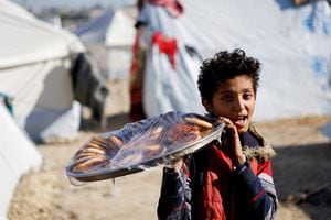 Un niño palestino desplazado, que huyó de sus casas debido a los ataques israelíes, lleva comida en una bandeja en un campamento de tiendas de campaña, en medio del conflicto en curso entre Israel y el grupo islamista palestino Hamas, en Rafah, en el sur de la Franja de Gaza, el 18 de enero de 2024.