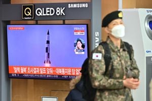 Un soldado surcoreano pasa junto a una pantalla de noticias de televisión que muestra imágenes de archivo de una prueba de misiles de Corea del Norte, en una estación de tren en Seúl el 5 de enero de 2022(Photo by Jung Yeon-je / AFP)