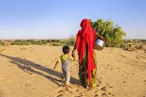 Mujer india llevando agua a la aldea. aldea del desierto, Rajasthan, India. El agua potable es muy valiosa en el desierto: las mujeres y los niños de Rajasthani a menudo caminan largas distancias a través del desierto para traer jarras de agua que llevan sobre la cabeza.