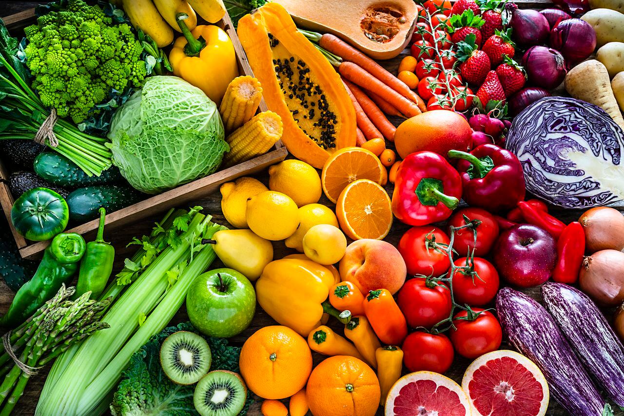 Vista de ángulo alto de una gran variedad de frutas y verduras orgánicas de color arco iris frescas saludables. La composición incluye repollo, zanahoria, cebolla, tomate, papa cruda, aguacate, espárragos, berenjena, apio, pepino, brócoli, calabaza, lechuga, espinaca, limón, manzanas, pera, fresas, papaya, mango, plátano, uva, naranjas. , kiwi entre otros. La composición está a la izquierda de un marco horizontal que deja un útil espacio de copia para el texto y / o el logotipo a la derecha. Captura digital de estudio de alta resolución de 42Mp tomada con lentes SONY A7rII y Zeiss Batis 40 mm F2.0 CF