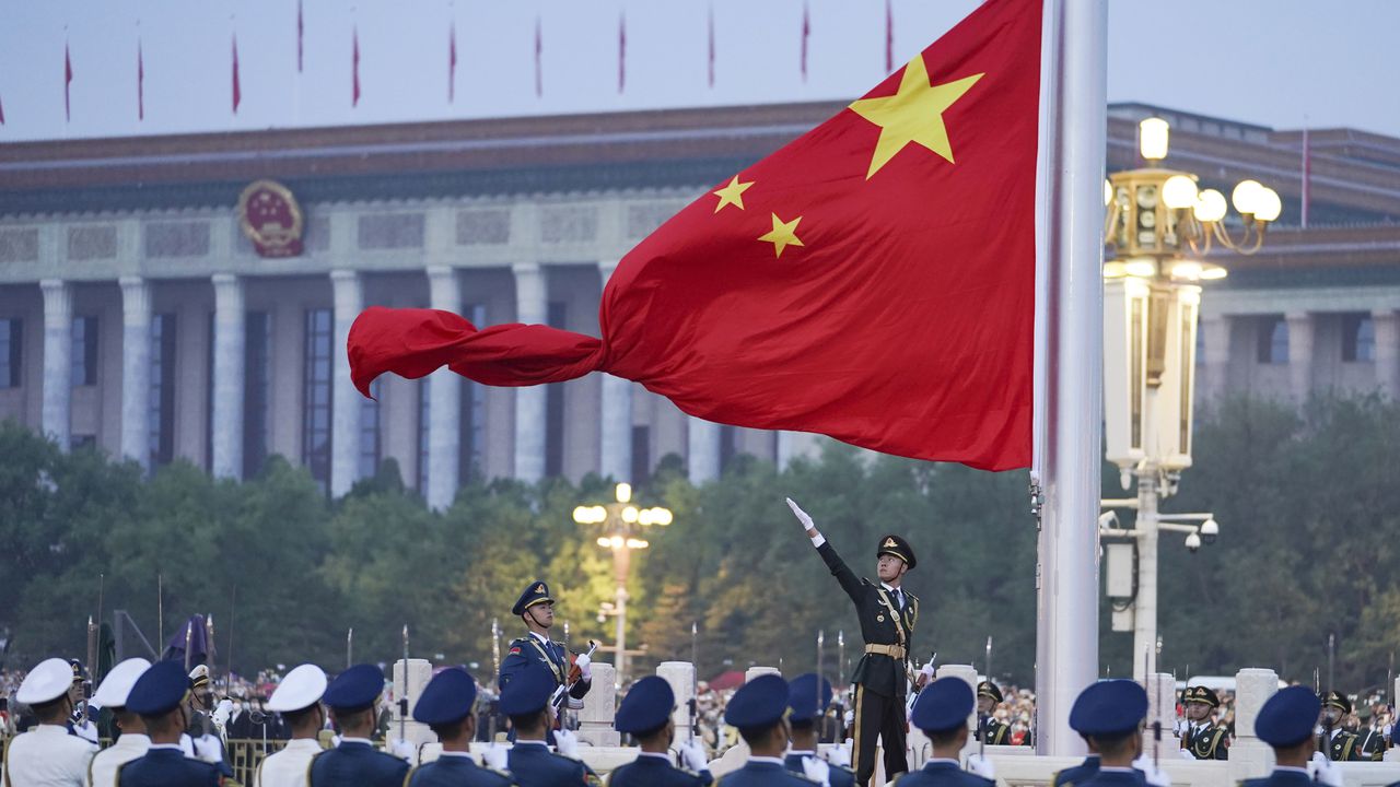 Un soldado de la guardia de honor desplega la bandera china durante una ceremonia en el 73er aniversario de la fundación de la República Popular China en la Plaza Tienanmen, Beijing