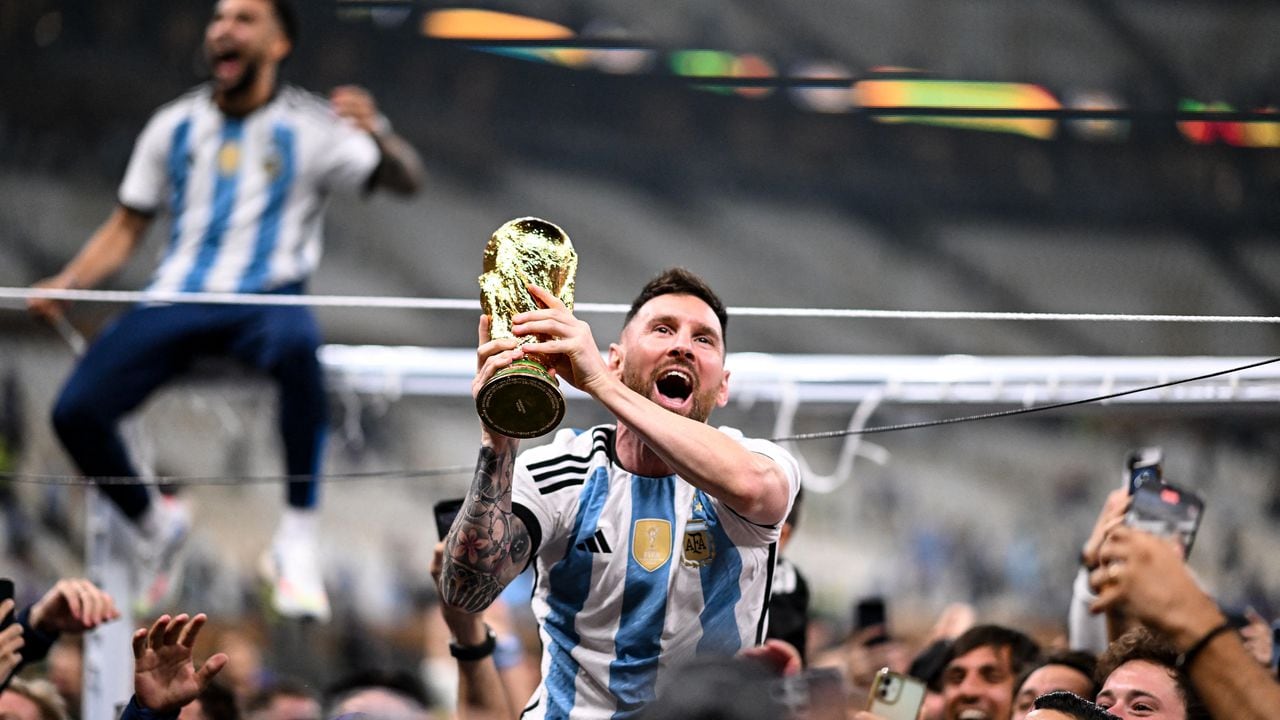 Argentina's forward #10 Lionel Messi lifts the FIFA World Cup Trophy as he celebrates with supporters winning the Qatar 2022 World Cup final football match between Argentina and France at Lusail Stadium in Lusail, north of Doha on December 18, 2022. (Photo by Kirill KUDRYAVTSEV / AFP)