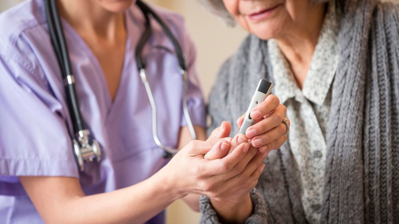 Nurse giving blood sugar test to patient in home