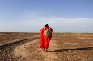 LA GUAJIRA, COLOMBIA - 24 DE SEPTIEMBRE: Una mujer lleva una canasta mientras camina sobre un terreno seco cerca del río Ranchería, donde vive el pueblo wayuu, luego de enfrentarse a la expansión de la mina de carbón Cerrejón en La Guajira, Colombia el 24 de septiembre. En el Provincial Reserva, una región semidesértica de Colombia, Cerrejón (la mina de carbón a cielo abierto más grande de Colombia y América Latina, y la décima más grande del mundo) ha creado desigualdades ambientales, problemas cardiovasculares, daños en la piel y contaminación. El río Ranchería ha transformado la dinámica del agua, afectando a los Wayuu. (Foto de Lis Mary Machado/Agencia Anadolu vía Getty Images)