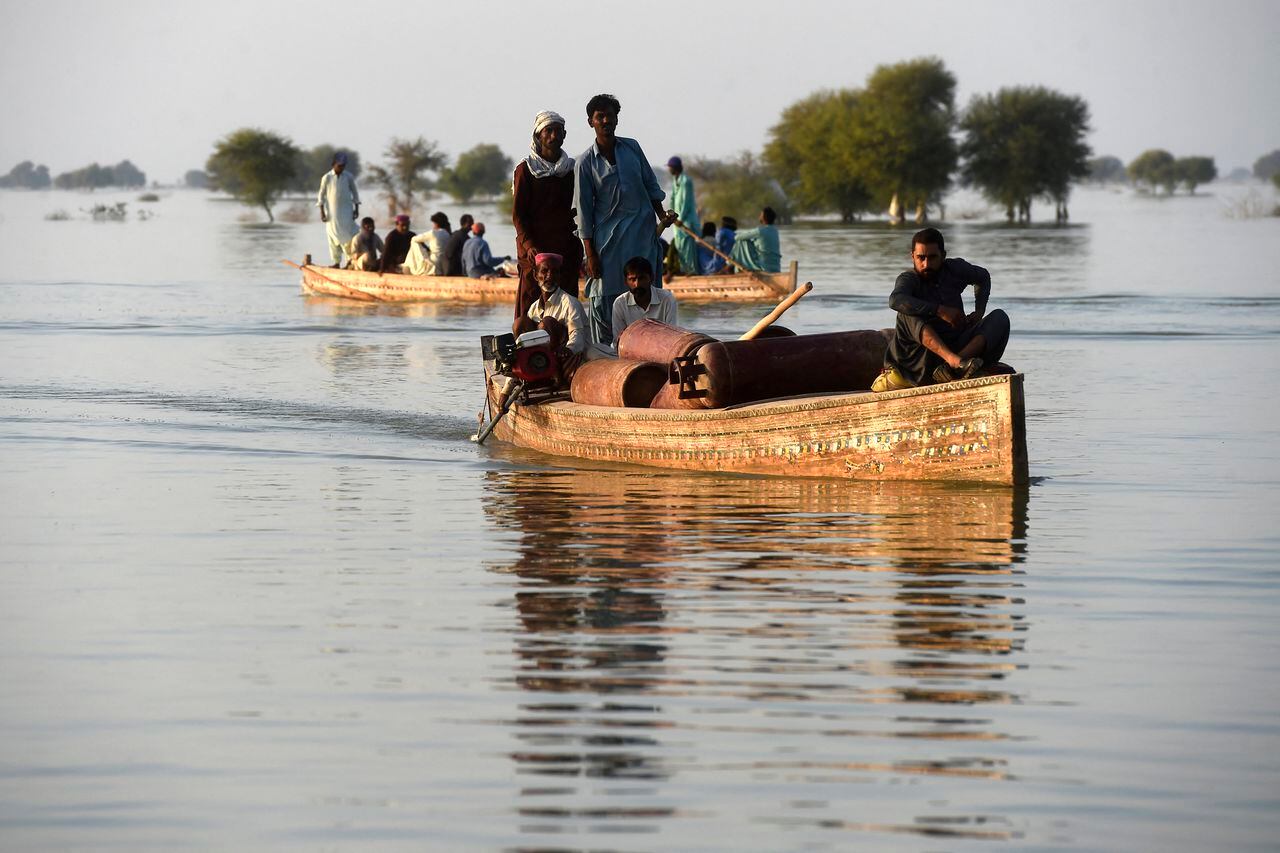 Los desplazados internos usan botes para cruzar un área inundada en Dadu, en la provincia de Sindh, el 27 de octubre de 2022. (Foto de Asif HASSAN / AFP)
