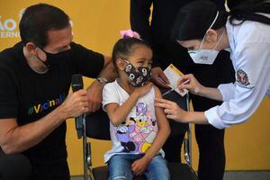 El gobernador de Sao Paulo, Joao Doria, mira a una niña que reacciona mientras recibe la primera dosis de la vacuna Pfizer-BioNTech contra el COVID-19, en el hospital Clínicas de Sao Paulo, Brasil, el 14 de enero de 2022.