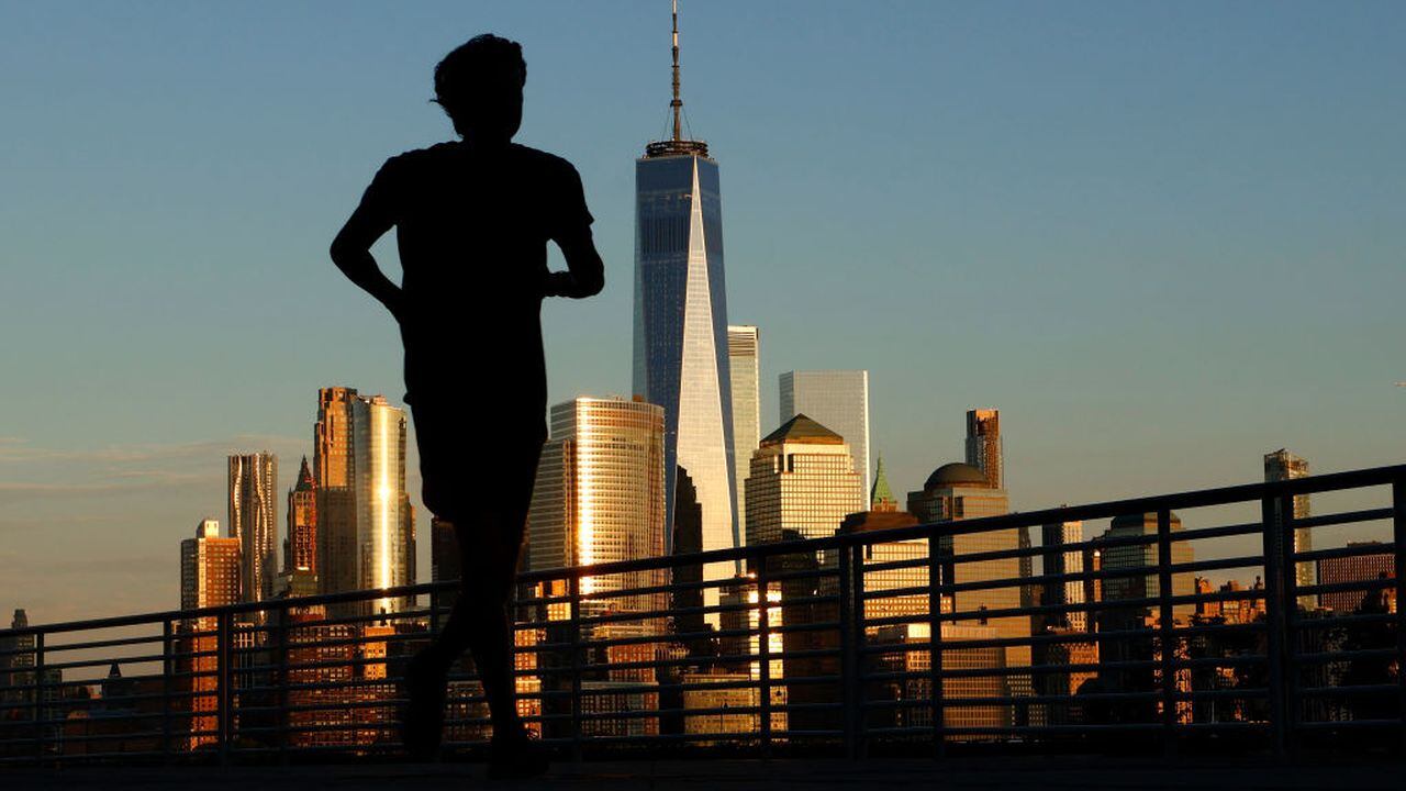 El sol se pone en el horizonte del bajo Manhattan y el One World Trade Center en la ciudad de Nueva York mientras una persona trota a lo largo del río Hudson el 31 de agosto de 2023, en Jersey City, Nueva Jersey. (Foto de Gary Hershorn/Getty Images)