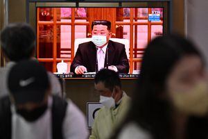 People sit near a screen showing a news broadcast at a train station in Seoul on May 12, 2022, of North Korea�s leader Kim Jong Un appearing in a face mask on television for the first time to order nationwide lockdowns after the North confirmed its first-ever Covid-19 cases. (Photo by Anthony WALLACE / AFP)