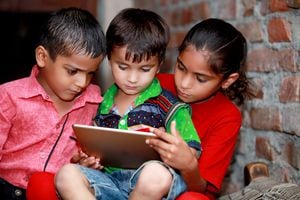 Pequeño grupo de niños del pueblo que sostienen una tableta digital y miran algo en ella.