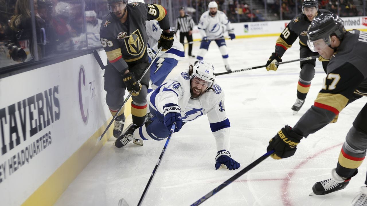 Tampa Bay Lightning left wing Pat Maroon (14) dives for the puck controlled by Vegas Golden Knights defenseman Ben Hutton (17) during the third period of an NHL hockey game Tuesday, Dec. 21, 2021, in Las Vegas. (AP/L.E. Baskow)