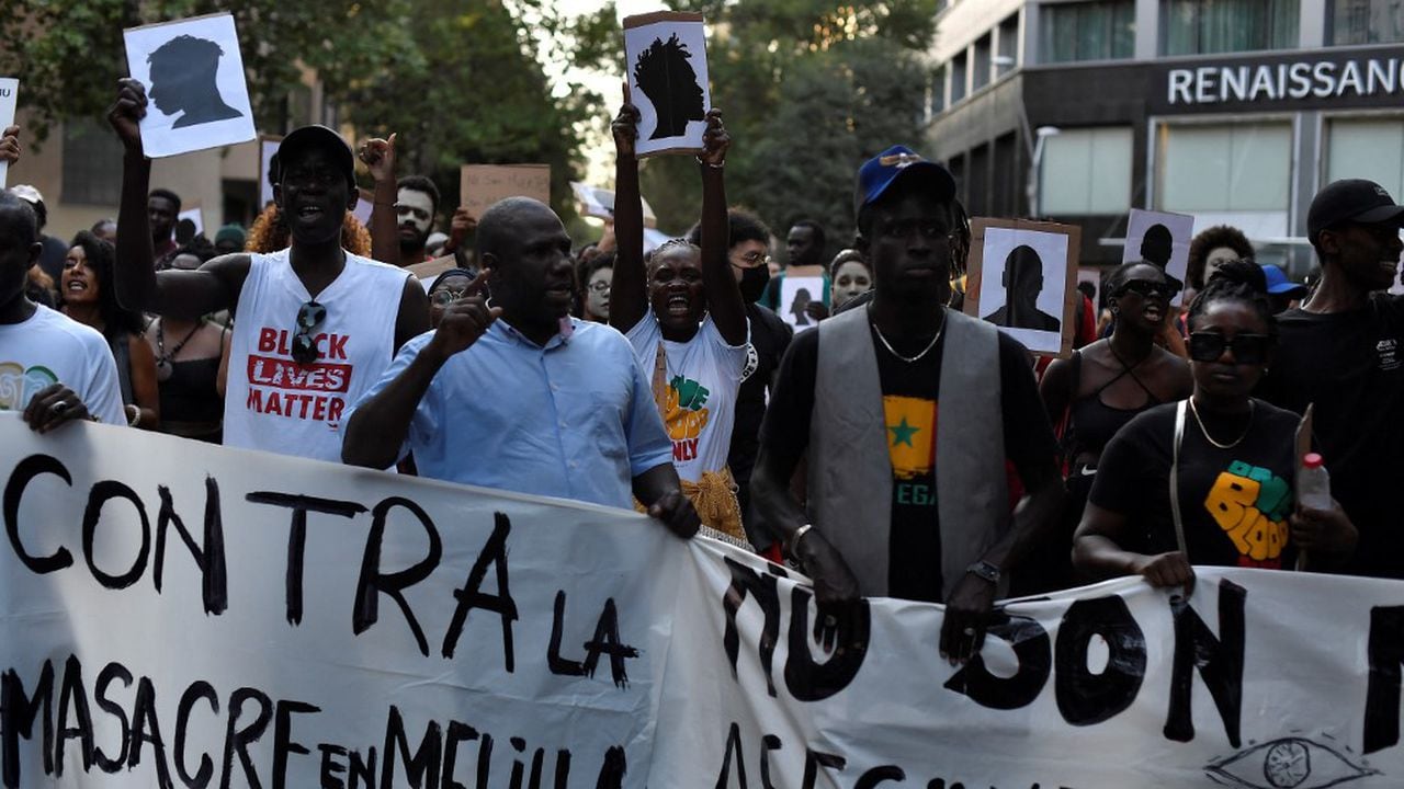 Manifestantes sostienen una pancarta que dice "Contra la masacre de Melilla" mientras participan en una manifestación antirracista "contra las muertes en las fronteras" en Barcelona el 1 de julio de 2022. - En la madrugada del 24 de junio, alrededor de 2.000 inmigrantes, en su mayoría del África subsahariana, trató de romper la valla de Marruecos a Melilla, uno de los dos pequeños enclaves de España en el norte de África. Las autoridades marroquíes dijeron que algunas de las víctimas se habían caído mientras intentaban trepar por la cerca, lo que dio un saldo inicial de 18 muertos, pero luego aumentó a 23 después de que otros cinco inmigrantes murieran a causa de sus heridas. (Foto de Pau BARRENA / AFP)