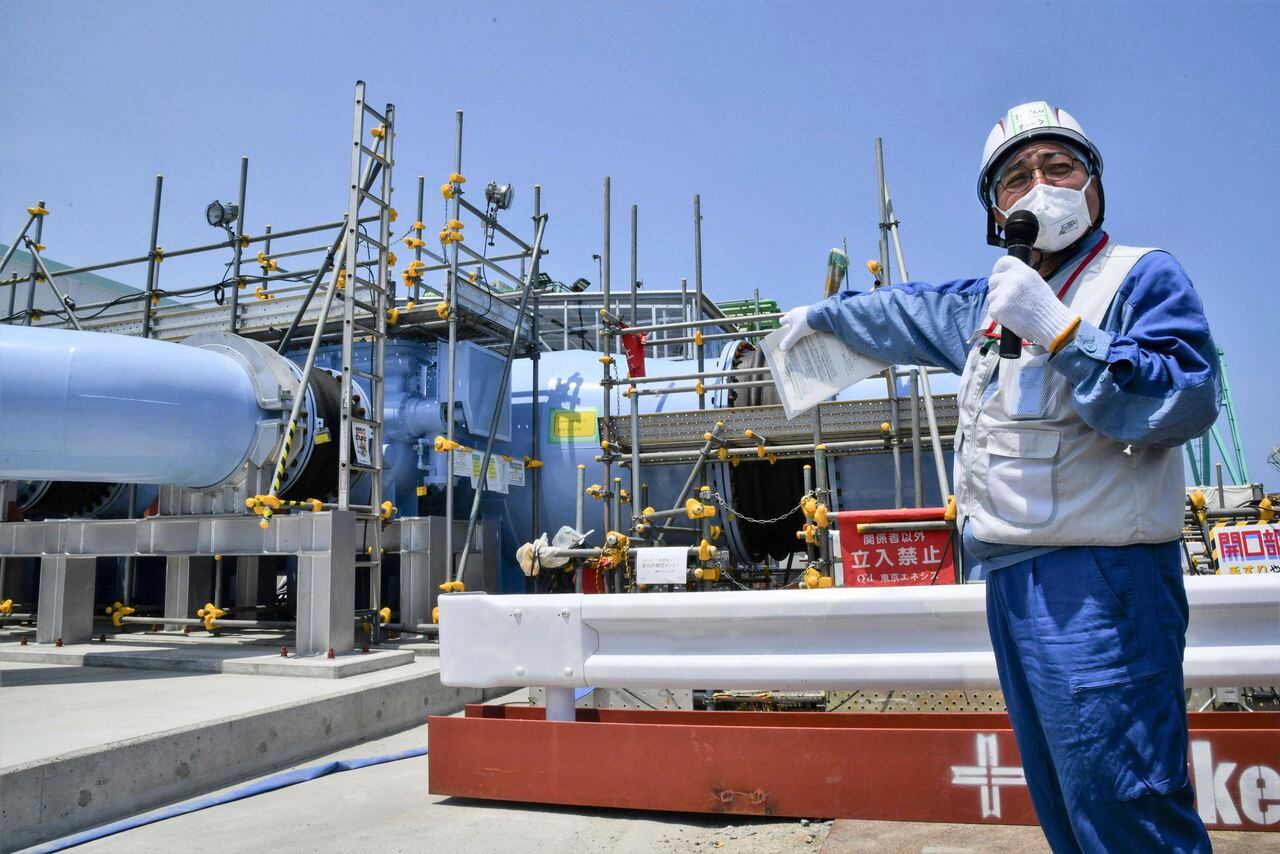 Un empleado del operador de la planta nuclear Fukushima Daiichi, Tokyo Electric Power Company Holdings (Tepco), explica la instalación que se utilizará para liberar al mar el agua radiactiva y tratada el lunes 26 de junio de 2023, en esa planta de Fukushima, en el norte de Japón. (Kyodo News vía AP)