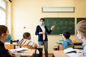 A teacher wearing a N95 Face masks teaches mathematics at an High School