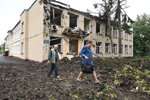 Los residentes locales pasan junto a un edificio dañado parcialmente destruido después de un bombardeo en la ciudad de Chuguiv, al este de Kharkiv, el 16 de julio de 2022. - En la región noreste alrededor de Kharkiv, la segunda ciudad de Ucrania, el gobernador Oleg Synegubov dijo que un ataque nocturno con misiles rusos mató tres personas en el pueblo de Chuguiv. (Foto de SERGEY BOBOK / AFP)