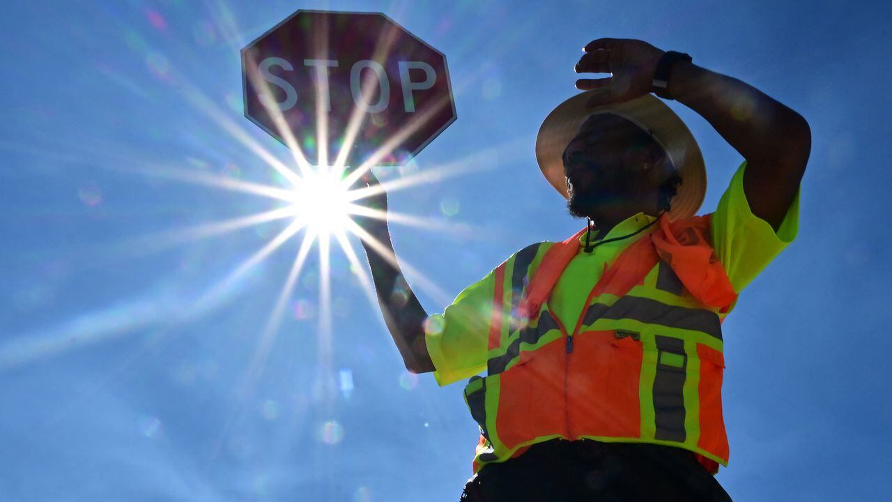 Un controlador de tráfico atiende la esquina de su calle durante un turno de 8 horas bajo el sol en Las Vegas, Nevada, el 12 de julio de 2023, donde las temperaturas alcanzaron los 106 grados en medio de una ola de calor en curso.