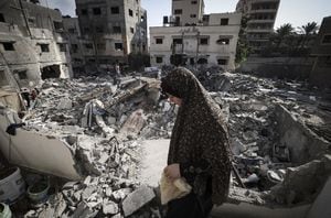 Una mujer palestina revisa los daños mientras camina entre los escombros frente a su casa en la ciudad de Gaza a principios del 8 de agosto de 2022, luego de un alto el fuego entre Israel y los militantes palestinos (Foto de Mahmud JAMONES / AFP)