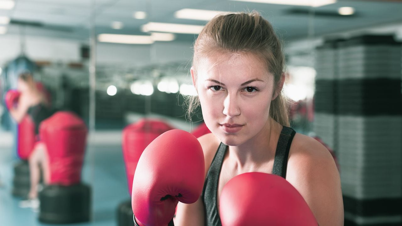 Retrato de mujer griega positiva que está entrenando en box gym.