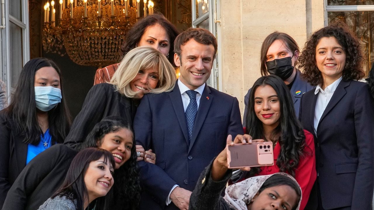 El presidente francés Emmanuel Macron (C) y su esposa Brigitte Macron posan para una foto grupal con los primeros galardonados de la Iniciativa Marianne para los Defensores de los Derechos Humanos luego de una ceremonia de premiación como parte del Día Internacional de la Mujer, en el palacio del Elíseo en París, en marzo. 8 de enero de 2022. (Foto de Michel EULER / POOL / AFP)