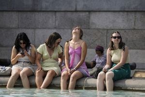 Un grupo de mujeres se refresca sumergiendo sus pies en la fuente de Trafalgar Square, en el centro de Londres, el 18 de julio de 2022 mientras el país experimenta una ola de calor extremo (foto de Niklas HALLE'N / AFP)