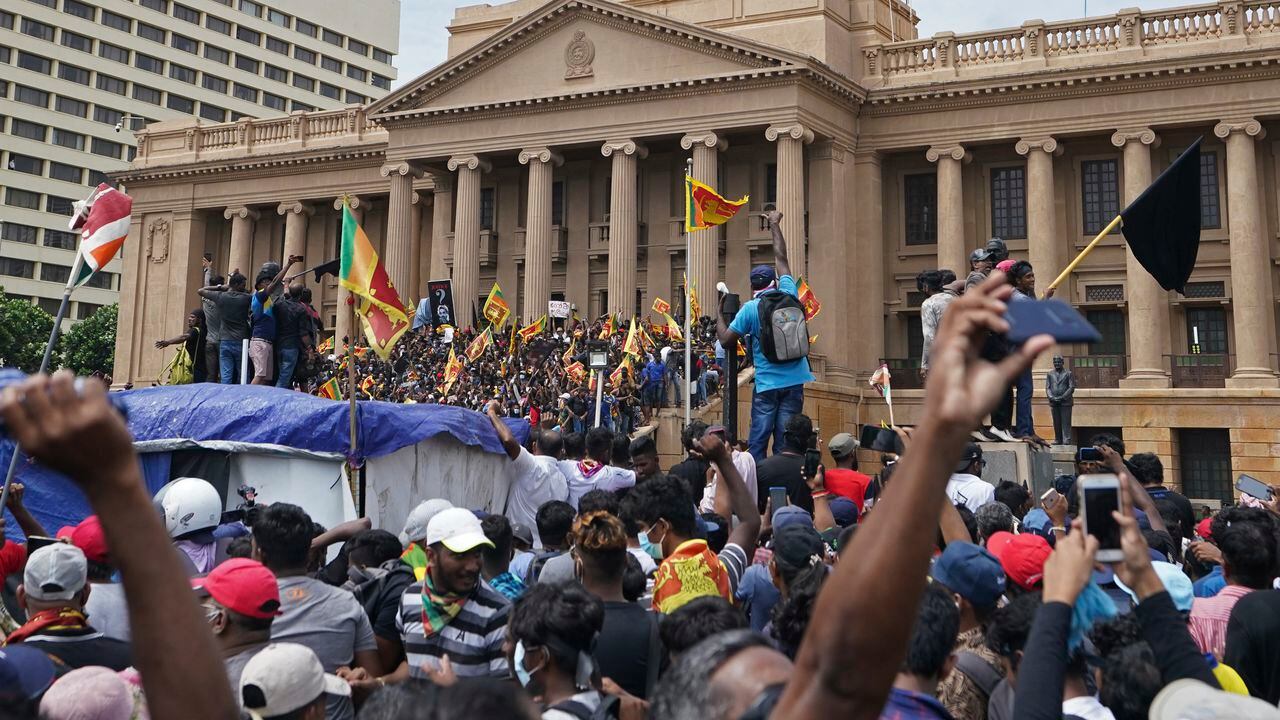 Manifestantes, muchos con banderas de Sri Lanka, se reúnen frente a la oficina del presidente.
