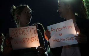 Dos mujeres llevan los mensajes "El aborto es un derecho" y "El aborto es atención sanitaria".