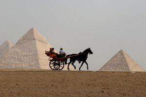 Los turistas montan un carro tirado por caballos frente a las pirámides de Giza, en las afueras de el Cairo, Egipto, 27 de octubre de 2022. 