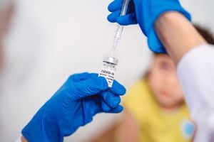 Médico con guantes protectores llenando una jeringa de inyección con la vacuna COVID-19 y listo para administrar la vacuna Covid-19 a una niña.