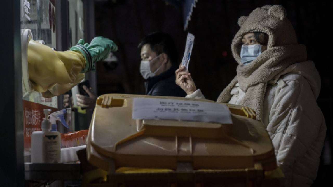 Una mujer muestra su hisopo y el kit de prueba a un trabajador sanitario antes de recibir una prueba de ácido nucleico para el COVID-19 en un centro de pruebas privado el 17 de enero de 2022 en Beijing, China. Imagen de referencia, no corresponde al hecho en mención (Foto de Kevin Frayer/Getty Images)