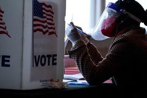 Una trabajadora electoral habla con un votante antes de que deposite su boleta el 3 de noviembre del 2020 en Atlanta. (AP Foto/Brynn Anderson)
