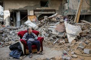 Un hombre palestino se sienta en un sillón frente a un edificio destruido en la ciudad de Gaza el miércoles 29 de noviembre de 2023, el sexto día del alto el fuego temporal entre Hamás e Israel.