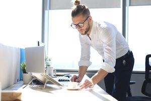 Hombre de negocios joven pensativo escribiendo algo mientras trabaja en el espacio de trabajo creativo