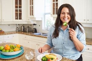 Mujer con sobrepeso comer comida saludable en la cocina sentado sonriendo a la cámara