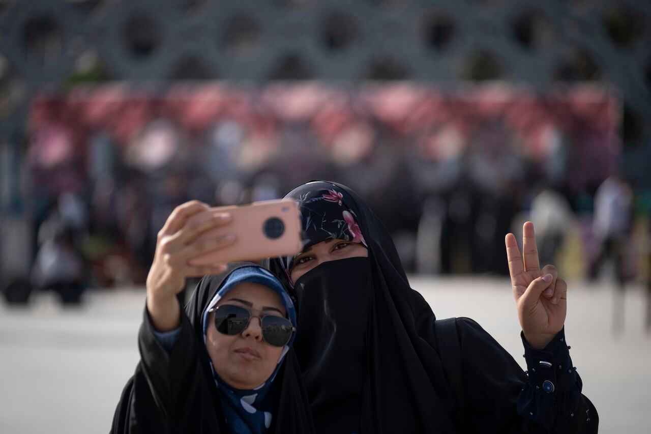 Una mujer iraní con velo hace un signo de victoria mientras se toma un selfie durante una manifestación en apoyo del Hijab y contra las mujeres que no usan el Hijab obligatorio, en el sur de Teherán, el 12 de julio de 2023.