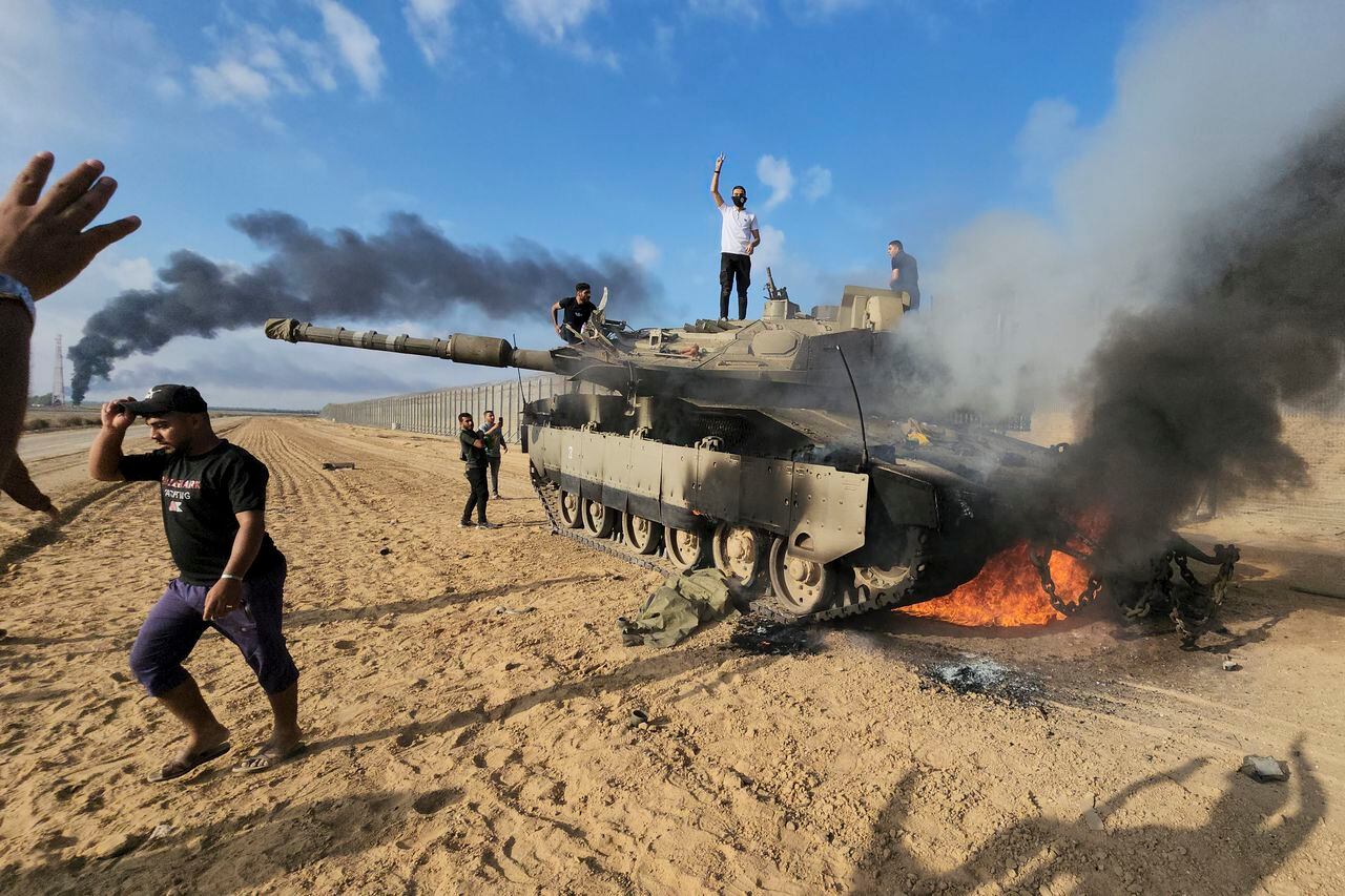Los palestinos celebran junto a un tanque israelí destruido en la valla de la Franja de Gaza al este de Khan Younis, al sur, el sábado 7 de octubre de 2023.