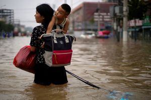 Una mujer que lleva a un niño y sus pertenencias vadea las aguas de la inundación después de las fuertes lluvias en Zhengzhou, provincia de Henan, China, el 23 de julio de 2021. Foto REUTERS/Aly Song Finalista del Premio Pulitzer de fotografía destacada