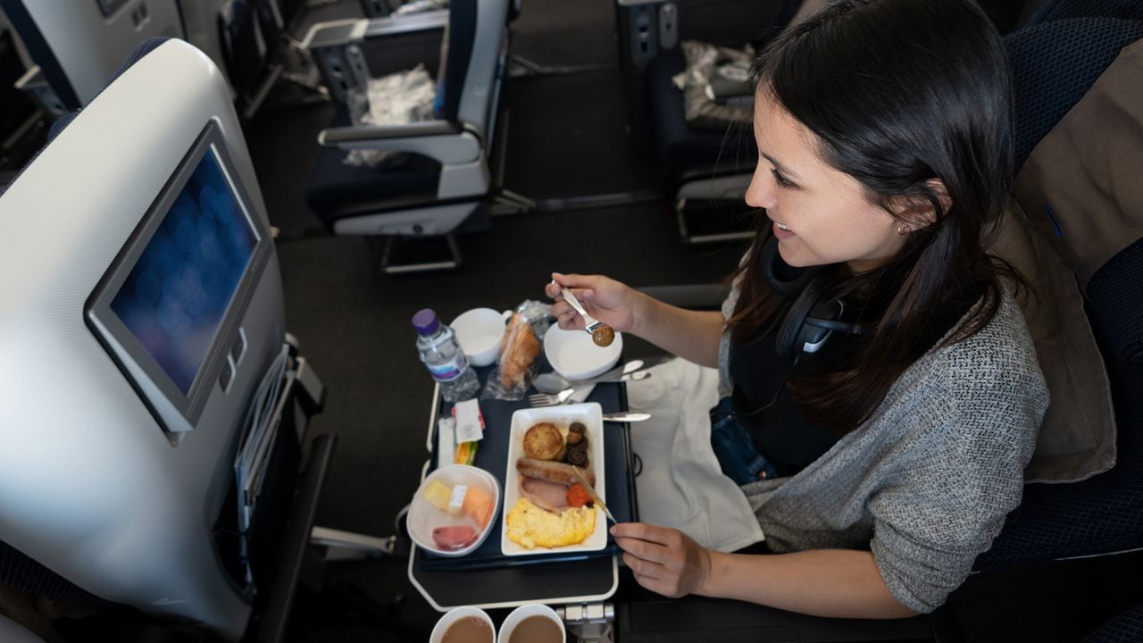 Una mujer viaja en avión y come a bordo - conceptos de viaje