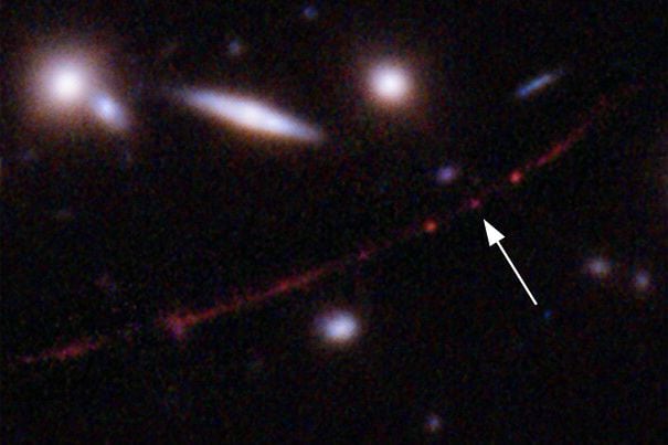 Esta imagen proporcionada por la NASA el miércoles 30 de marzo de 2022 muestra la estrella Earendel, indicada por una flecha, y la galaxia Sunrise Arc, que se extiende desde la parte inferior izquierda hasta la parte superior derecha, doblada ópticamente debido a un cúmulo de galaxias masivo entre ella y el Hubble.