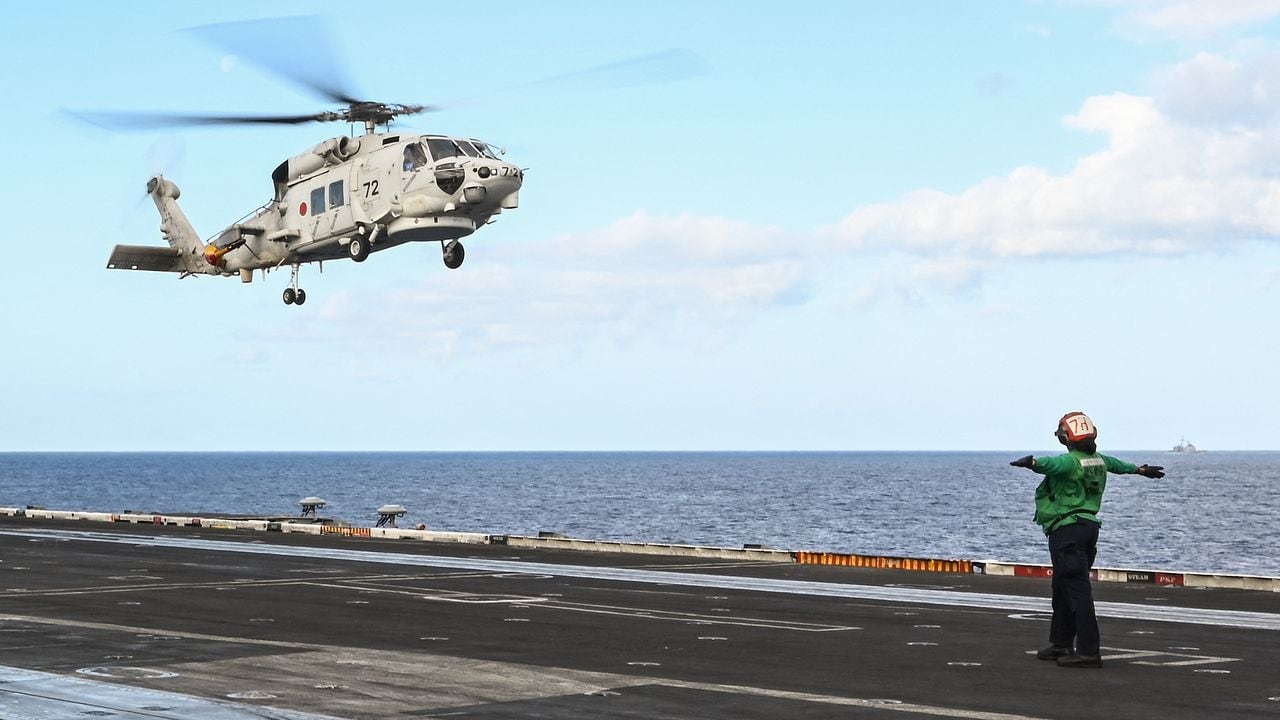 Esta foto tomada el 31 de enero de 2024 muestra un helicóptero SH-60K de la Fuerza de Autodefensa Marítima de Japón aterrizando en la cubierta del portaaviones USS Carl Vinson durante un ejercicio marítimo de tres días entre Estados Unidos y Japón en el Mar de Filipinas. Una importante operación de búsqueda continuó frente a Japón el 22 de abril de 2024 para buscar a siete personas desaparecidas después de que dos helicópteros SH-60K de la marina aparentemente chocaran durante el fin de semana, y se confirmó la muerte de un miembro de la tripulación.