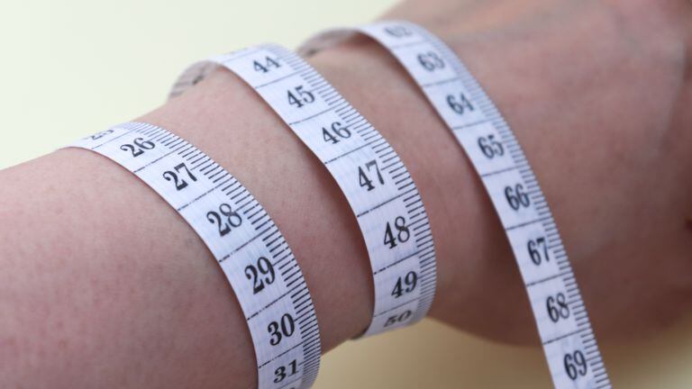 Close-up image of a tape measure around one's wrist.