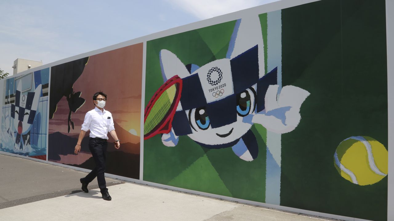 Un hombre camina frente a murales que promueven los Juegos Olímpicos, que están programados a iniciar en julio de 2021, el lunes 24 de mayo de 2021, en Tokio. (AP Foto/Koji Sasahara)