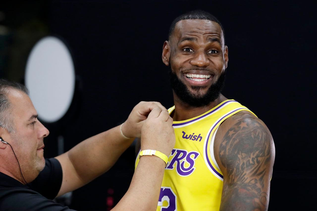 FILE - Los Angeles Lakers' LeBron James smiles as a microphone is placed on his jersey during media day at the NBA basketball team's practice facility Sept. 24, 2018, in El Segundo, Calif. James announced earlier in the year his departure from Cleveland and signing with the Lakers. (AP Photo/Marcio Jose Sanchez, File)