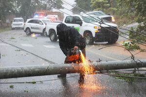 Un trabajador corta un poste de electricidad que fue derribado por el huracán Fiona mientras bloqueaba una carretera en Cayey, Puerto Rico, el domingo 18 de septiembre de 2022.