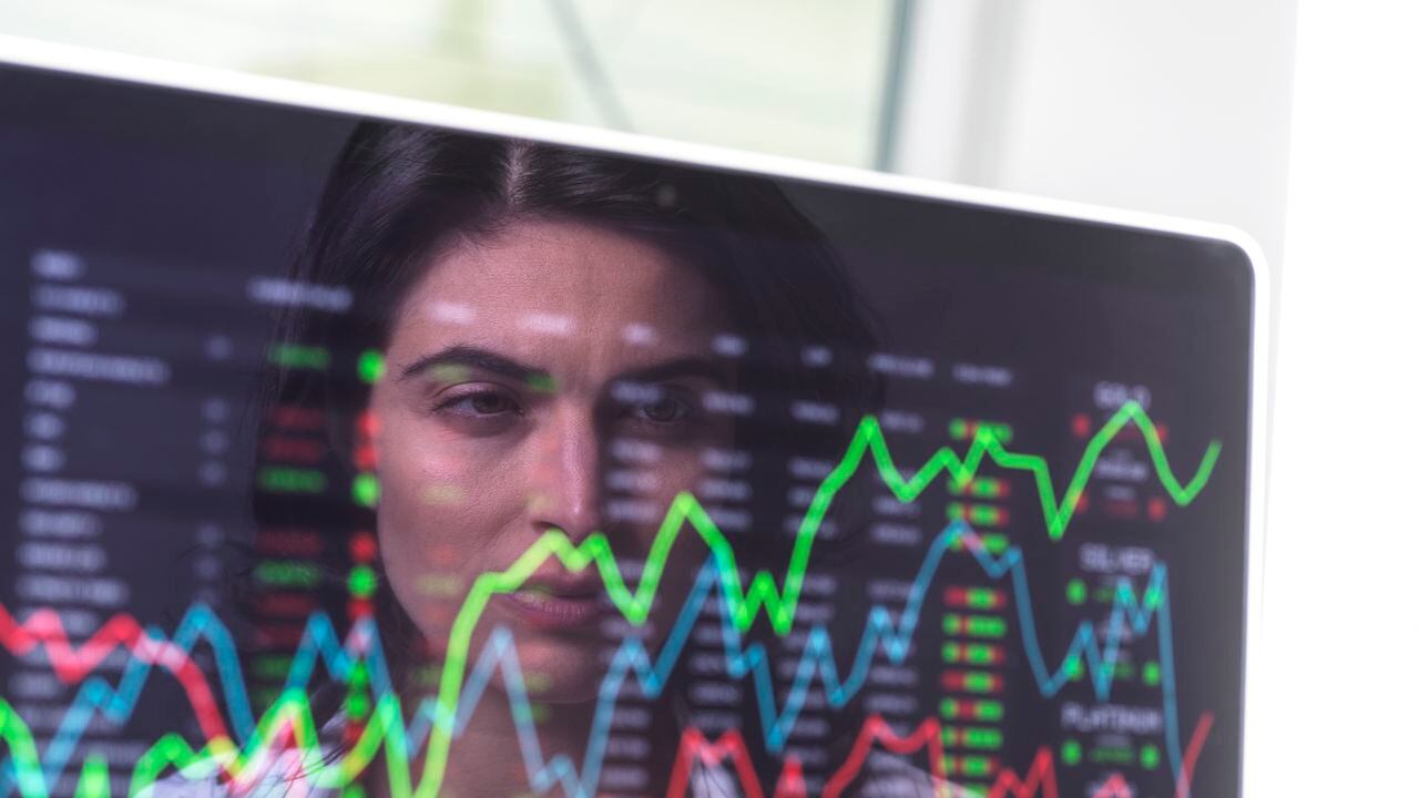 Analista de sexo femenino que ve los datos del mercado financiero en una pantalla.