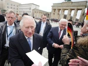 El rey Carlos III de Gran Bretaña, al frente, saluda a los fanáticos en la Puerta de Brandenburgo en Berlín, Alemania, junto con el presidente alemán Frank-Walter Steinmeier, atrás, el miércoles 29 de marzo de 2023. (Kay Nietfeld/dpa via AP)
